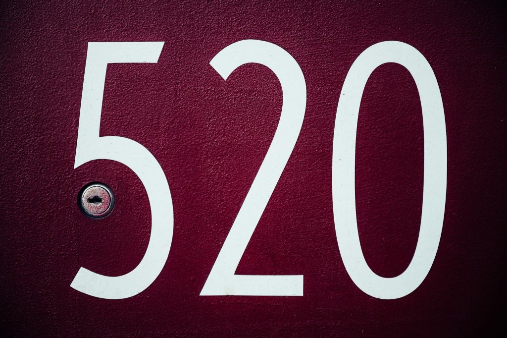 Close-up image of a red residential door with the number 520 and a keyhole.