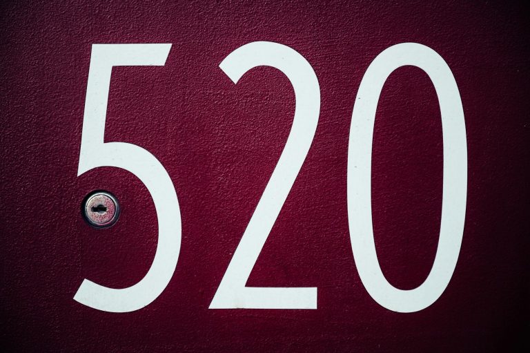 Close-up image of a red residential door with the number 520 and a keyhole.